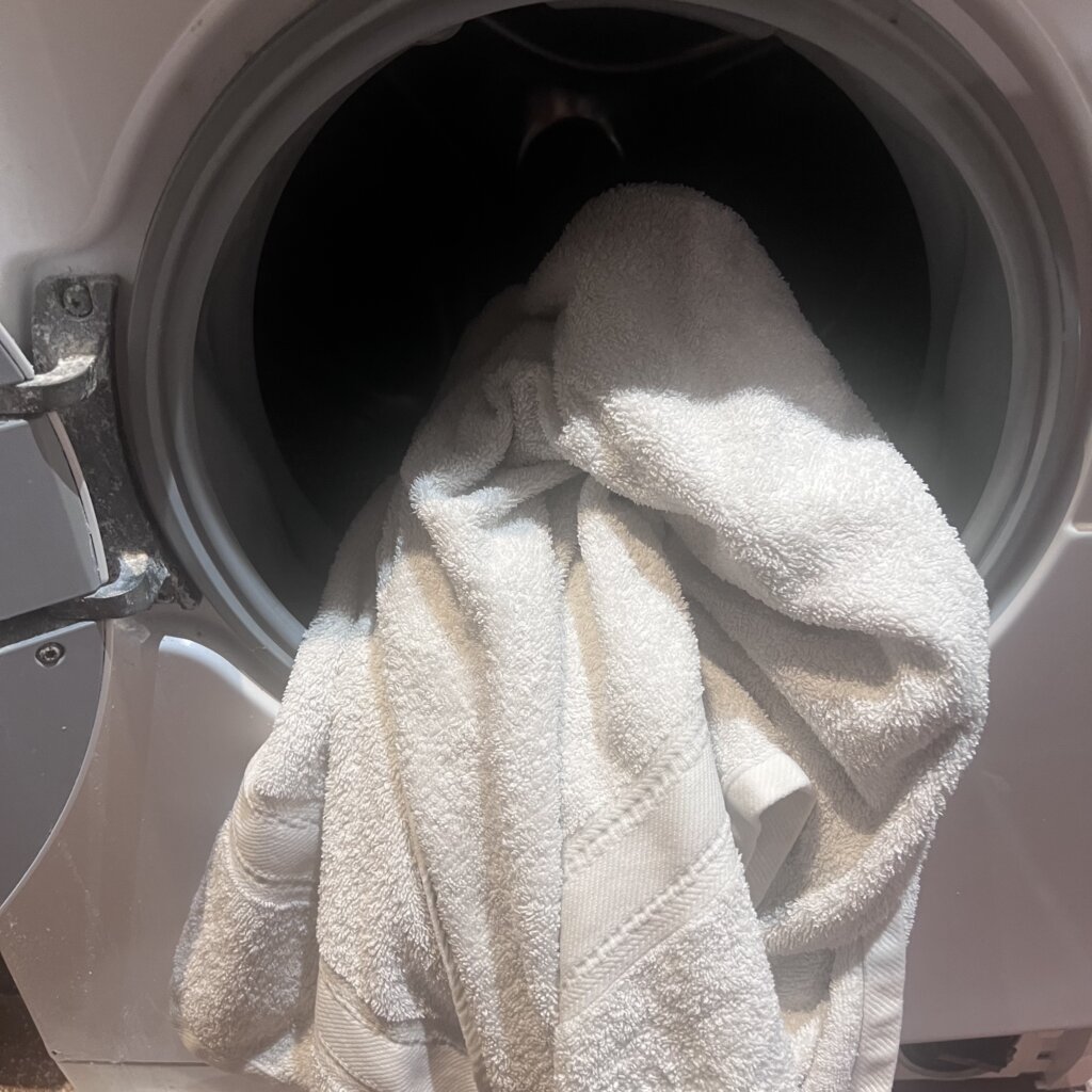 White towel partially inside washing machine - the very towel that helps with my sensory sensitivites